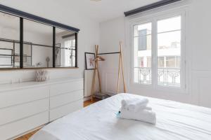 - une chambre blanche avec un lit et un miroir dans l'établissement Chic 1br near Paris and the Bois de Vincennes in Saint-Mandé Welkeys, à Saint-Mandé