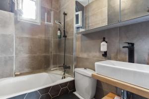 a bathroom with a tub and a sink and a toilet at Appartement Pouchard Welkeys in Saint-Mandé
