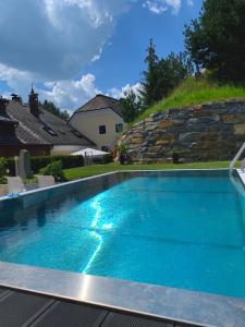 a swimming pool with blue water in front of a house at Ferienwelt Bogensperger in Mariapfarr