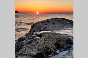 una roca en el océano con una puesta de sol en el fondo en Joecen Apartment, en Marsaskala