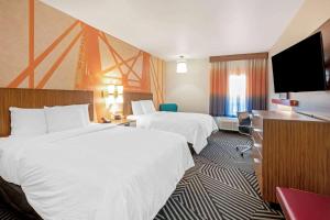 a hotel room with two beds and a flat screen tv at La Quinta by Wyndham Waco Baylor Downtown in Waco
