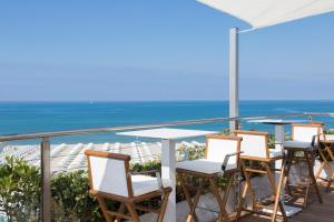 a row of chairs and tables on a balcony with the ocean at Grand Hotel Principe Di Piemonte in Viareggio