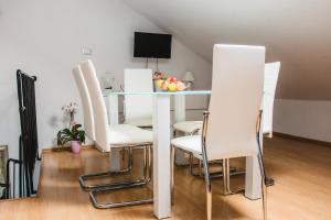 a dining room with a table and white chairs at Apartmani Tena in Selce