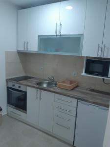 a kitchen with white cabinets and a sink and a microwave at Apartman Lipa in Bar