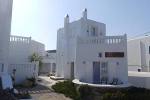 ein großes weißes Gebäude mit Stühlen davor in der Unterkunft Mykonos Ornos RedOcher Home in Ornos