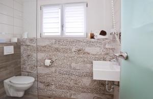 a bathroom with a toilet and a sink and a window at Pension Kramer in Grafenhausen