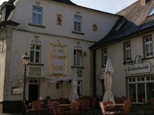 un edificio con sillas y sombrillas delante de él en Hotel Rauch, en Attendorn