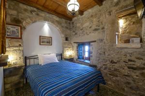 a bedroom with a bed in a stone wall at Venetiko Apartments in Naxos Chora