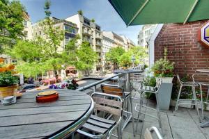eine Außenterrasse mit Tischen, Stühlen und einem Sonnenschirm in der Unterkunft Hotel Senator Hamburg in Hamburg