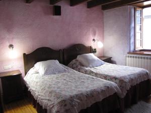 ガロスにあるHostal Plaça Garósのピンクの壁のベッドルーム1室(ベッド2台付)