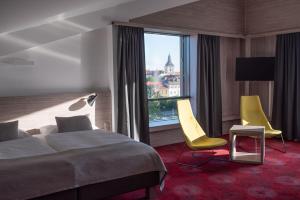 une chambre d'hôtel avec un lit, deux chaises et une fenêtre dans l'établissement Hotel TAMMEL, à Jičín