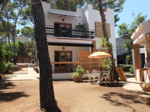 a white house with a table and an umbrella at Entre Pinos PB Beach Apartment in Torredembarra