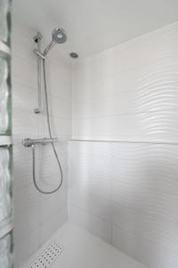 a shower in a bathroom with white tiles at Piaf in Paris