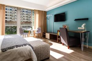 a bedroom with a bed and a desk and a television at WINK Aparthotel Foreshore in Cape Town