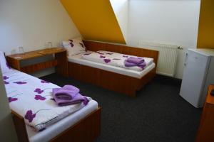 two beds in a room with purple towels on them at Restaurace a penzion Lutena in Dolní Lutyně