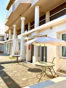 two tables and an umbrella in front of a building at Rainbow Apartments in Ayia Napa