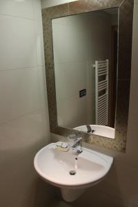 y baño con lavabo blanco y espejo. en Hostal Burbia en Villafranca del Bierzo