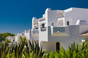 Un edificio blanco con árboles delante. en Clube Albufeira Garden Village, en Albufeira