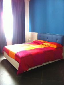 a large bed with colorful sheets and a blue wall at Campo Allegro in Santa Ninfa