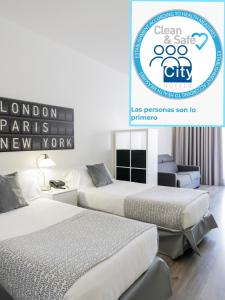 Dos camas en una habitación con un cartel que dice London Parks New York en Aparthotel Atenea Calabria, en Barcelona