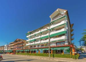 a tall building with green and white balconies on a street at Tino Hotel & SPA in Ohrid