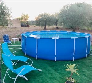 einen großen blauen Pool mit zwei Stühlen und einem Tisch in der Unterkunft Villa Luce in Modica