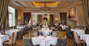uma sala de jantar com mesas e cadeiras brancas e um lustre em InterContinental Dublin, an IHG Hotel em Dublin
