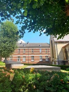 a large brick building with a tree in front of it at Studio Belga Begijnhof Tongeren in Tongeren