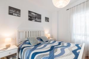 ein weißes Schlafzimmer mit einem Bett mit blauen und weißen Streifen in der Unterkunft Anna Triana Boutique Apartament in Sevilla + 38 Fotos