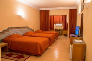 a hotel room with two beds and a television at Chems Le Tazarkount in Afourer