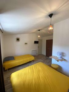 two beds in a room with yellow sheets at La Cigogne in Éclaron