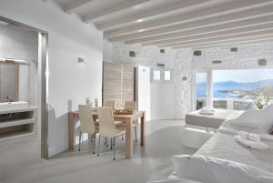 a white bedroom with a dining table and a bed at Crystal Suites in Mýkonos City