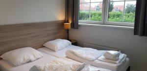 twee bedden met kussens in een kamer met een raam bij de Putter in Hollum