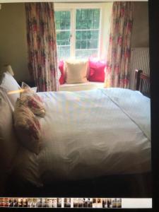 uma cama com lençóis brancos e almofadas num quarto em Horse & Hound Inn em Broadway