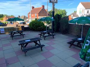 3 mesas de picnic con sombrillas en un patio en White Horse Tavern en Telford