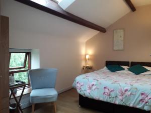 um quarto com uma cama, uma cadeira e uma janela em Brook Barn B&B em Hale