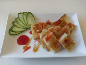 a white plate with some food on it with cucumbers at Warm B&B in Magong