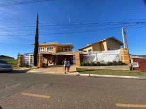 a woman walking down a street in front of a house at Casa de Campo Alto Padrao in Piracaia