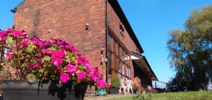 a brick building with a large pot of pink flowers at Brook Barn B&B in Hale