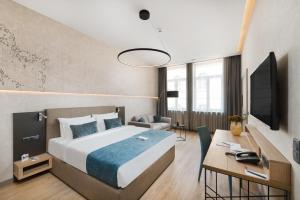 um quarto com uma cama, uma secretária e uma televisão em Hotel Vision Budapest by Continental Group em Budapeste