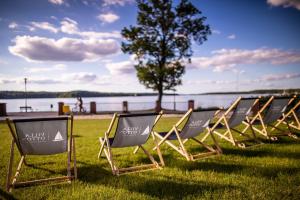 a row of lawn chairs sitting in the grass by the water at OTTON-Charzykowy Bed&Restaurant in Chojnice