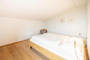 a white bed in a room with white walls at LAAX Homes - Casa Fau in Laax