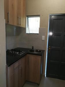 a kitchen with a sink and a black refrigerator at Salas Stay, Midrand in Midrand