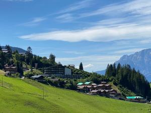 a village on a green hill with mountains in the background at Apartment Andrea in Maria Alm am Steinernen Meer