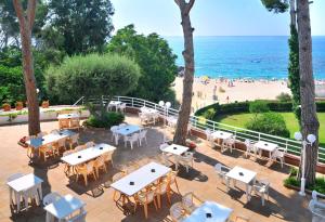 un patio al aire libre con mesas y sillas y una playa en GHT Xaloc, en Platja d'Aro