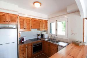 a kitchen with wooden cabinets and a white refrigerator at Villa ELSIE in Arenal d'en Castell