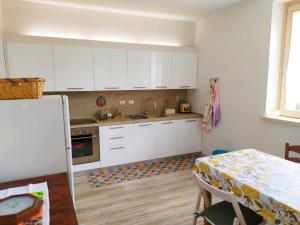 Appartamento Corte dei Landi في Cavriago: مطبخ مع دواليب بيضاء وطاولة وطاولة وطاولة وطاولة طعام