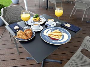 una mesa con platos de comida y dos vasos de zumo de naranja en Urbihop Hotel, en Vilna