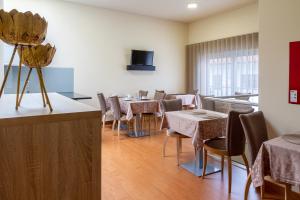 a dining room with tables and chairs and a tv at Boutique Mouras in Mondim de Basto