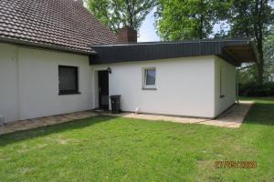 a white house with a grass yard at Frisch renovierte Ferienwohnung auf idyllischem Pferdehof in Beverstedt